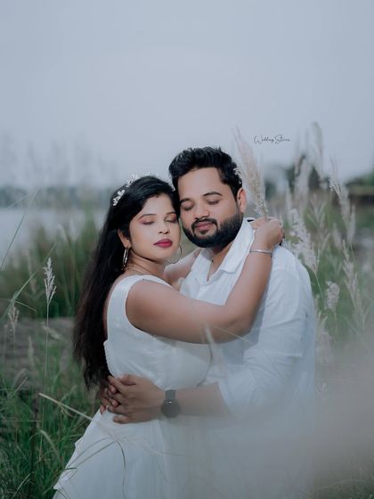 A serene and romantic portrait with eyes closed, as if the couple is lost in the moment. The soft focus on the foreground grass adds a dreamy quality.