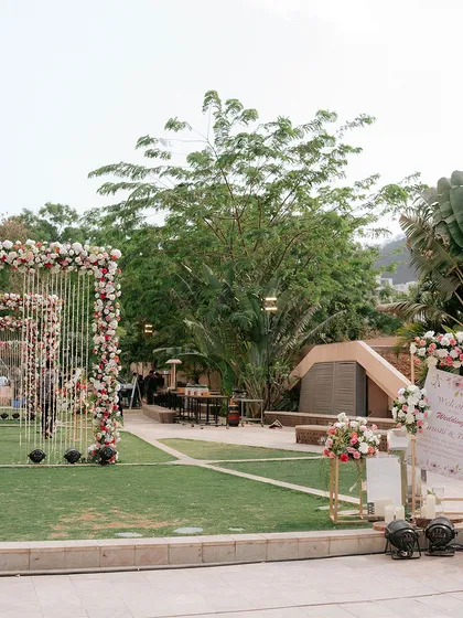 An outdoor wedding entrance featuring a series of floral arches that create a beautiful, immersive pathway for guests.