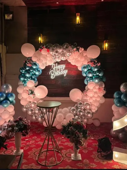 A stylish and modern first birthday celebration. This setup features a rustic-chic balloon ring in white and silver, a glowing neon "Happy Birthday" sign, and a large light-up number '1' to mark the special milestone.