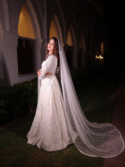 A candid shot of the bride in the white lehenga, smiling. This photo captures the joy and elegance of the moment.