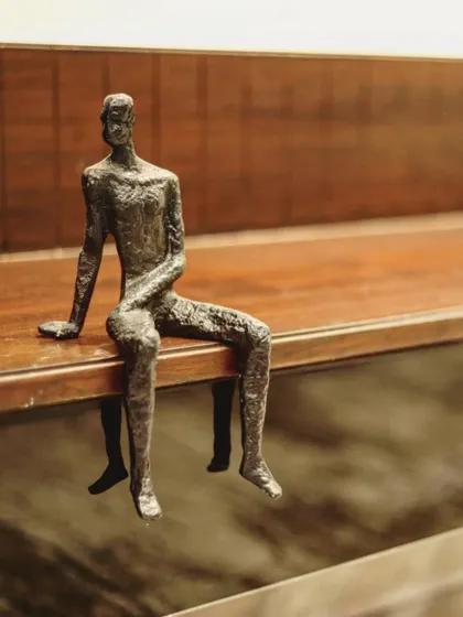 A small, bronze figurine sits on the edge of a wooden shelf, adding a humanistic and artistic detail to the interior decor. These small touches help make a house feel like a home.