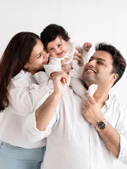 Sometimes, the simplest moments are the most beautiful. This family portrait was taken against a clean, minimalist white background to keep all the attention on their happy connection and the baby's infectious giggle.