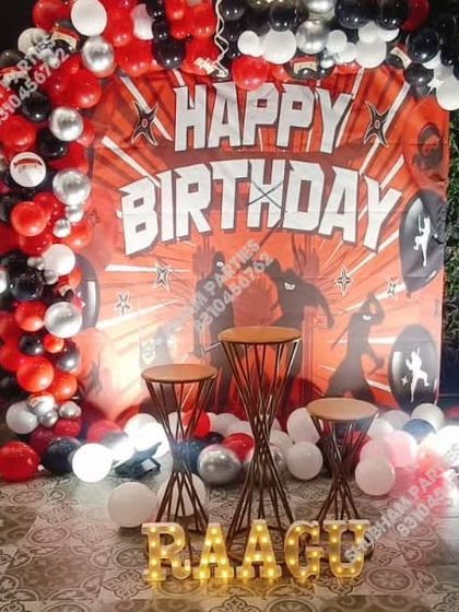 A dynamic ninja-themed birthday party with a red, black, and silver balloon arch.