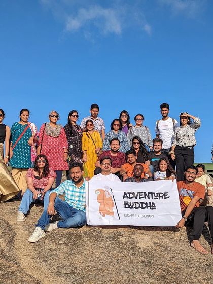 Our group posing with the Adventure Buddha banner on a sunny day at Antharagange. The rocky landscape is perfect for some light bouldering and exploration.