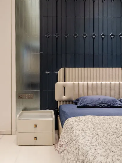 A detailed look at the textured navy blue headboard, which serves as a stunning focal point. The combination of different materials and patterns adds depth and sophistication to the bedroom design.
