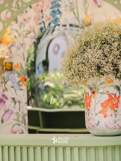 We use custom prints to tie our design elements together. Here, a floral-printed vase holding a cloud of baby's breath sits in front of a matching floral backdrop, creating a sense of depth and cohesion.