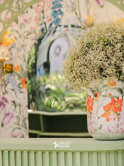 A detail shot showing the layers of pattern and texture, from the floral-print vase to the custom-printed wallpaper in the background.