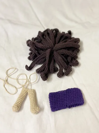 The beginning of a surfer doll named Tabias. This photo shows his legs, a purple headband, and his unique brown hair, all waiting to be assembled.
