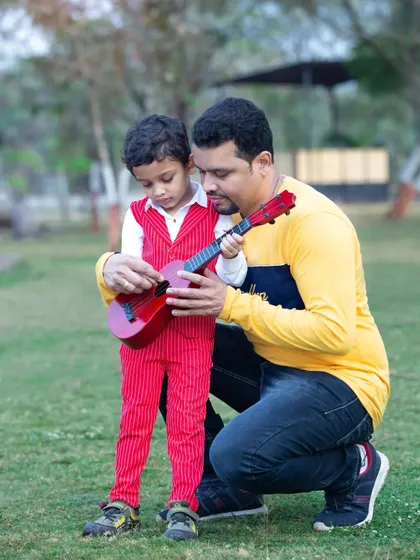 A father teaches his son how to play the guitar in a sweet, candid moment.