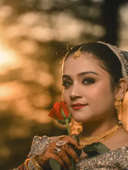 A stunning close-up of the bride holding a rose, her face illuminated by the golden sunset during her reception shoot.