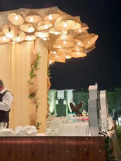 A rustic bar setup featuring a unique chandelier made from woven baskets, creating a warm and inviting focal point for the event.