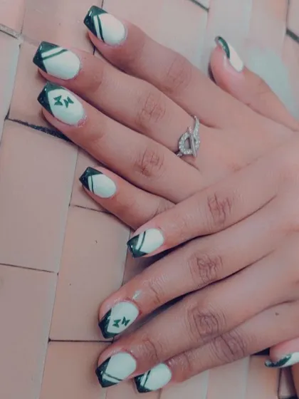 A unique take on a French manicure with black tips, abstract white lines, and tiny butterfly details.