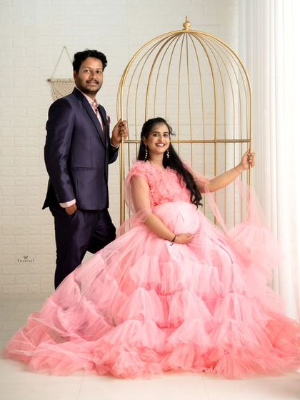 This couple's maternity photo uses a golden birdcage prop for a unique and elegant studio setup. The pink gown adds a soft, romantic touch.