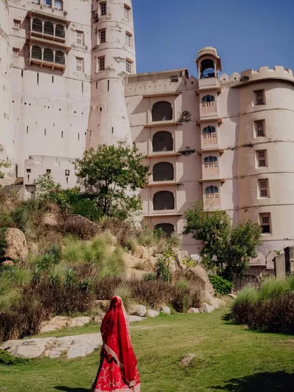 A bride in her striking red lehenga walks towards the Alila Fort, a modern maharani beginning her new chapter. The location and styling come together to tell a powerful story.