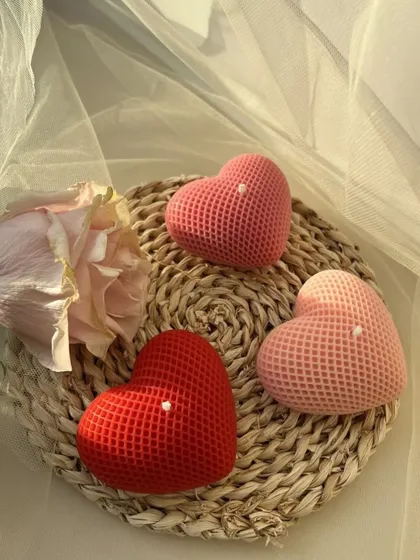 A trio of red and pink honeycomb heart candles on a woven placemat.