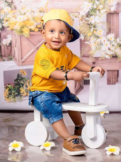 A cool dude cruising through childhood. This little boy in a bright yellow shirt and cap looks ready for a fun day out on his tricycle.