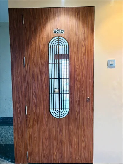 A direct front view of the wooden safety door, showing the clean lines and the house number plate.