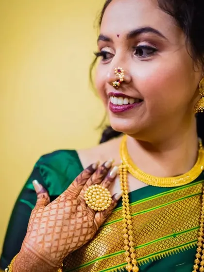 The bride's henna-adorned hand beautifully frames her face in this shot. Her makeup features a soft smokey eye and a berry lip, which pairs perfectly with her gold jewelry.