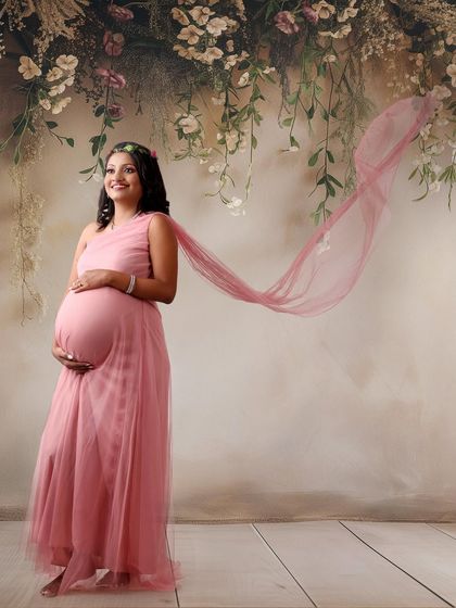 A lovely pink gown with a sheer train tossed in the air for a beautiful, flowing effect. The floral headband adds a soft, bohemian touch to the look.