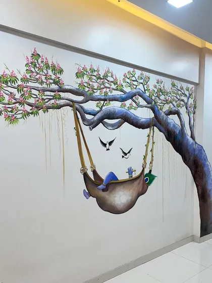 This realistic wall mural of Baby Krishna sleeping in a swing under a tree brings a sense of calm and innocence to the room.
