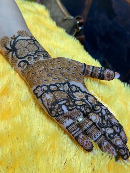 A close-up of a peacock and elephant design on the hand. These motifs are symbols of grace and good luck.