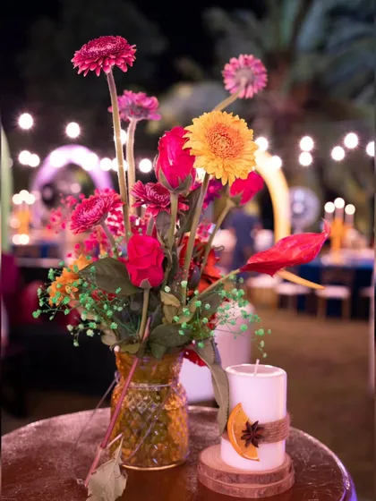 A colorful floral arrangement in a yellow vase, paired with a candle wrapped in cinnamon and star anise. These small, fragrant details added a sensory layer to the eclectic tablescapes.
