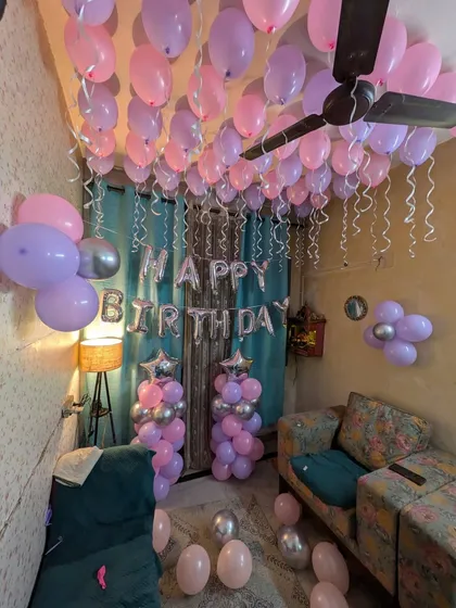 The 'Happy Birthday' banner and balloon pillars serve as the main backdrop in this living room birthday setup.