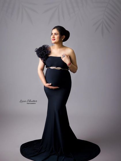 A sophisticated portrait in a black gown, with a shadow of leaves adding a touch of nature-inspired artistry to the studio shot.