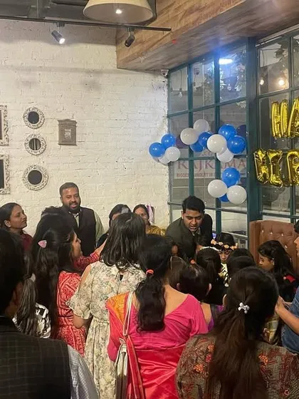 A candid shot of a magic show at a restaurant party. The guests are gathered around, enjoying the performance, which adds a great interactive element to the celebration.