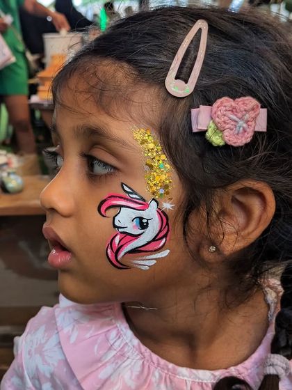 A sweet unicorn face paint with a touch of gold glitter, adding a little extra magic.