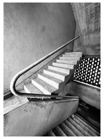 The play of light and shadow on this under-construction staircase highlights its sculptural qualities. A perforated screen in the background hints at the layers of the facade.