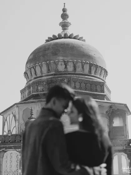 A soft-focus, romantic black and white portrait with the dome of Vijay Vilas Palace in the background. This artistic shot emphasizes the emotion and intimacy between the couple, with the architecture serving as a timeless witness.