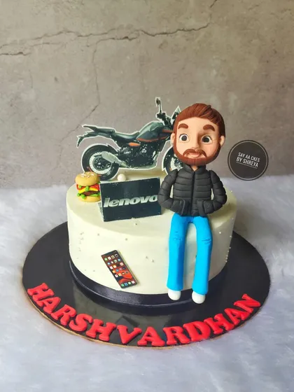 This cake captures a person's life in a few key details. It features a custom figurine, along with his passions for motorcycles and tech, and his work at Lenovo, creating a personalized birthday story.