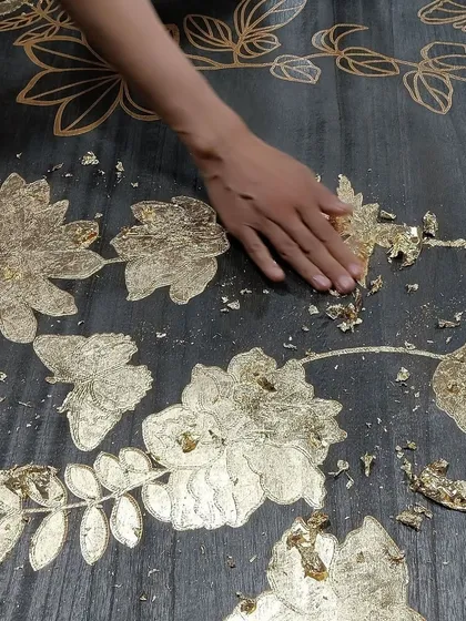 This video showcases the meticulous hand-application of metallic leaf onto our Flourish wallcovering. This sophisticated design uses laser-cut technology on genuine wood veneer to create a luxurious, large-scale mural.
