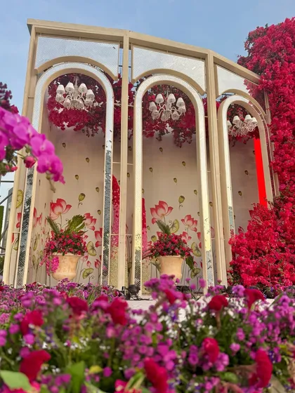 A view from below, looking up at the mirrored arches and the cascade of red and purple flowers. This perspective highlights the scale and immersive quality of the decor.