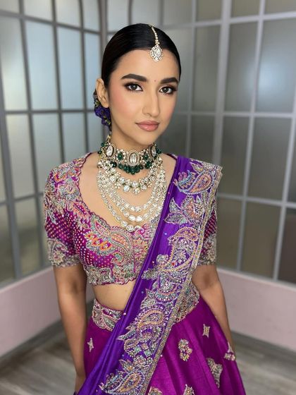 A stunning look created for a masterclass, showcasing a bold purple lehenga. The makeup is clean and sharp, with a flawless base and defined eyes, letting the vibrant color of the outfit be the hero.