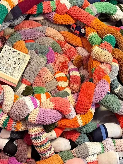 A close-up of the coiled sculpture made from upcycled socks for the 'Goblin Mode' installation. The vibrant colors and soft textures create a playful and inviting form.