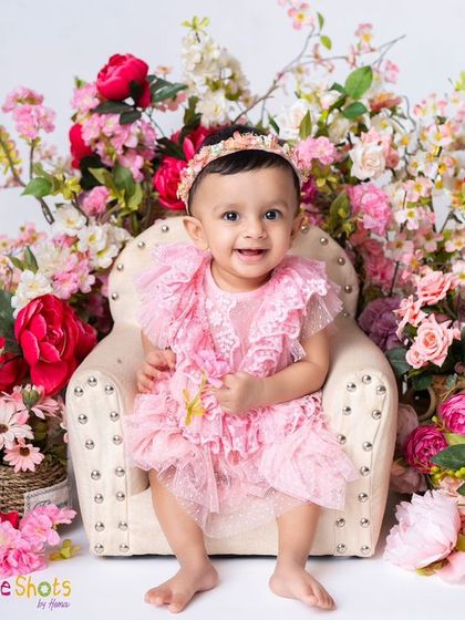 A perfect little lady sitting on her miniature armchair, surrounded by a garden of pink flowers. This is a beautiful and elegant setup for a sitter session.