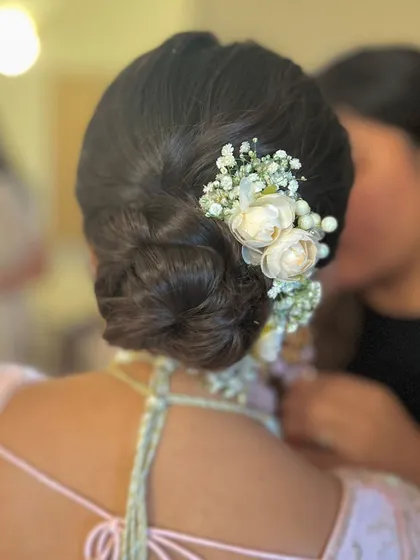 A soft and romantic bun with a cascade of white flowers and baby's breath. This is a beautiful choice for a reception or evening event.