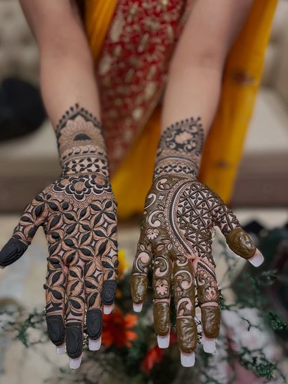 This design uses negative space effectively to make the bold, dark patterns stand out. The fingertips are dipped in henna for a traditional finish.