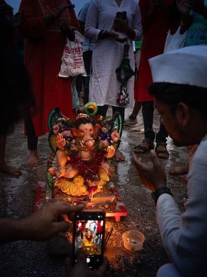 A devotee takes a photo of a Ganesha idol during Ganesh Chaturthi, a modern act of devotion that captures the blend of tradition and technology.