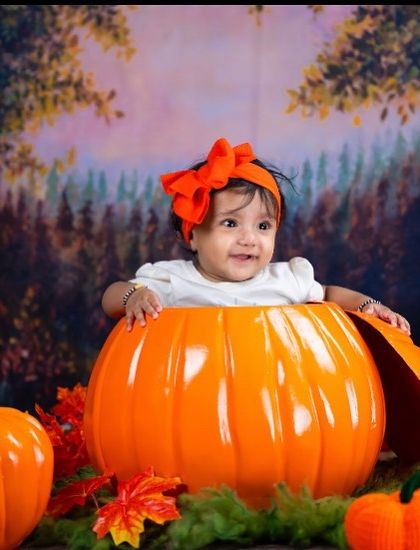 Peek-a-boo from a pumpkin! This autumn-themed shoot is perfect for the fall season, with a giant pumpkin prop and colorful leaves.