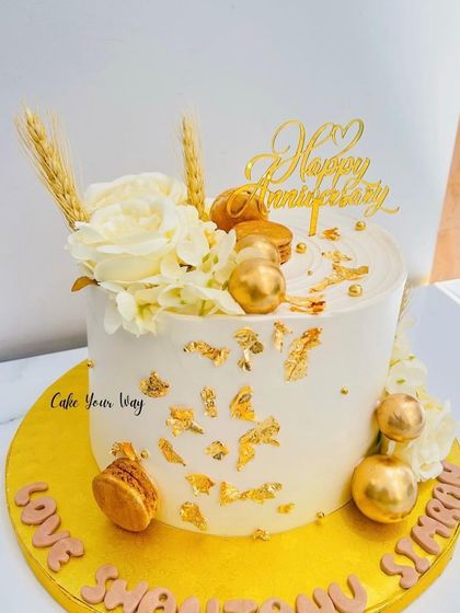 Gold accents and sweet memories. An elegant anniversary cake with macarons and wheat stalks.