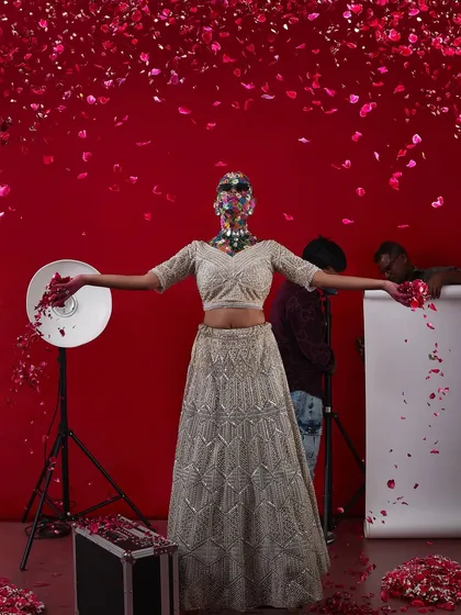 A creative and artistic bridal shot, with the model's face covered in flowers, set against a backdrop of falling petals.