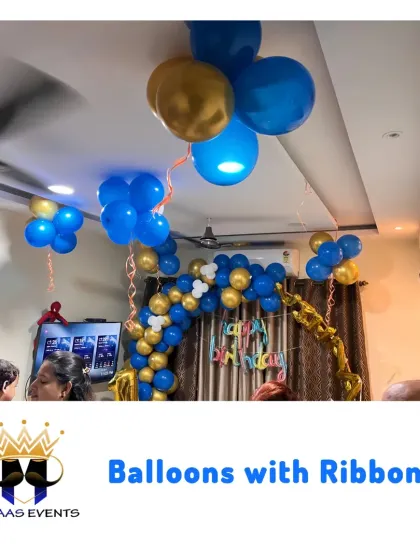 Balloons with ribbons hanging from the ceiling create a fun and celebratory atmosphere. This setup in blue and gold is perfect for a boy's birthday party at home.