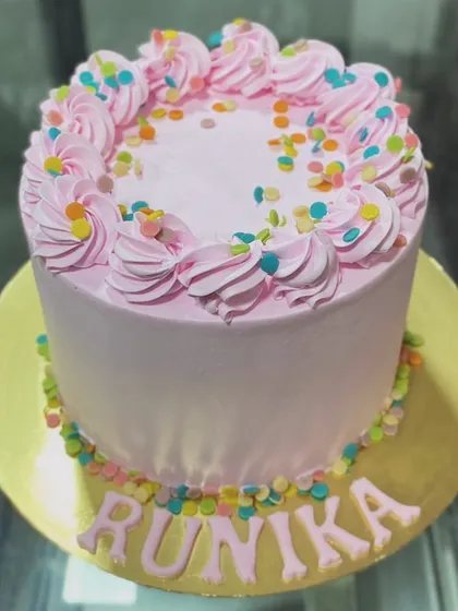 A simple and joyful pink cake with colorful sprinkles, personalized for Runika.