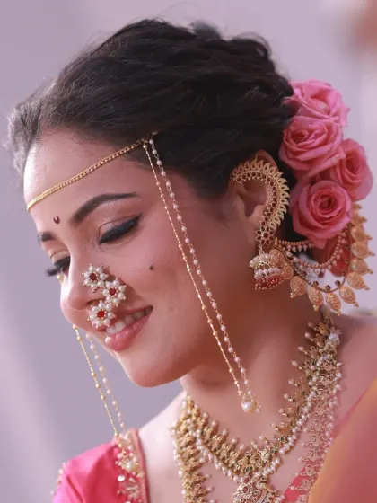 A close-up profile shot highlighting the delicate floral hair accessory and the intricate details of her nath.