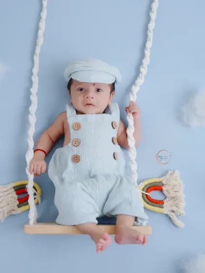 A seated perspective on the swing, this pose is perfect for capturing a calm, awake newborn in a creative setting.