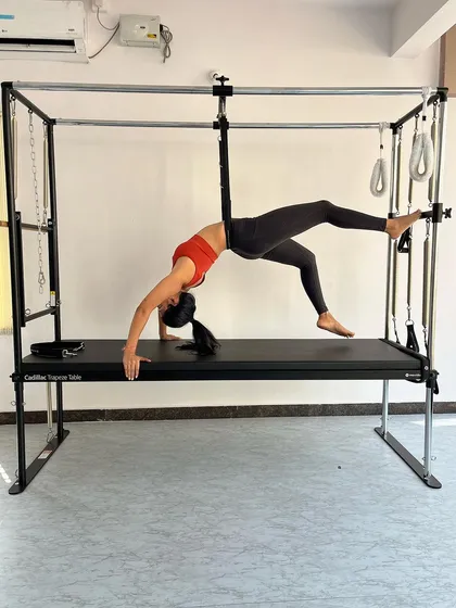 A stunning bridge variation on the Cadillac, using the hanging straps for support to deepen the backbend and open the chest.