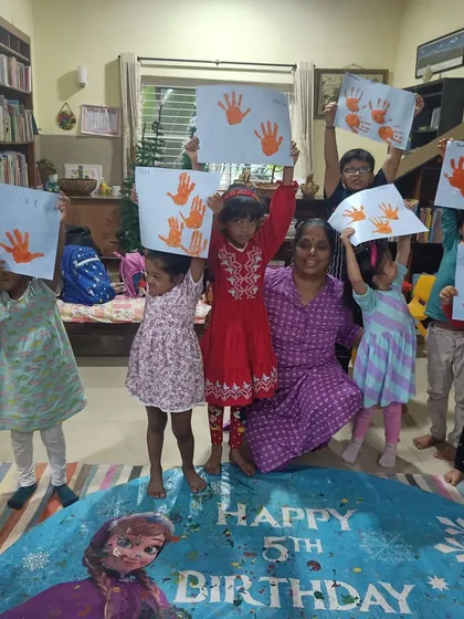 Happy faces and proud hands hold up handprint art. This sensory activity was part of a birthday celebration at our library, making for a memorable and creative day.